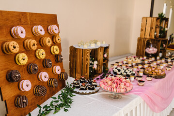 Candy bar. Table with different sweets for party. Wooden wedding decor. Different candies, cupcakes, souffle and cakes. Decorated in nature and eco theme, indoor.