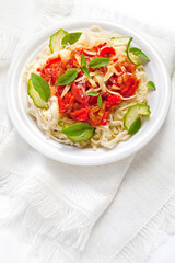 Pasta with tomato sauce basil and grated parmesan on the white plate