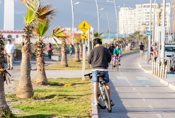 young man standing with a bicycle looking at cellphone or mobile device with headphones on a bikeway in La Serena
