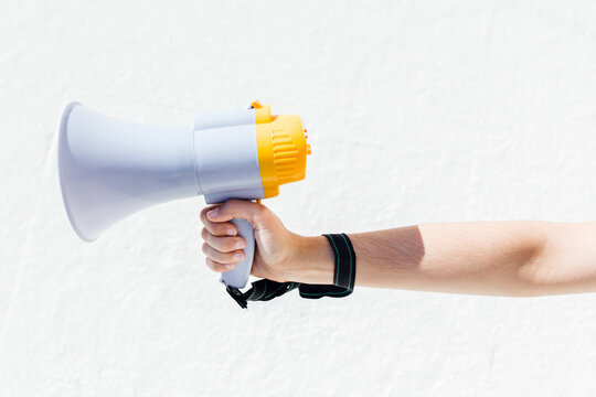 Woman holding megaphone by white wall