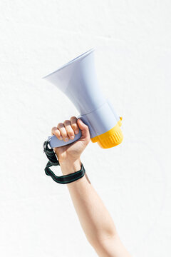 Woman holding megaphone in front of white wall