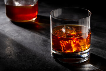 Whiskey bottle and whiskey glass with ice.