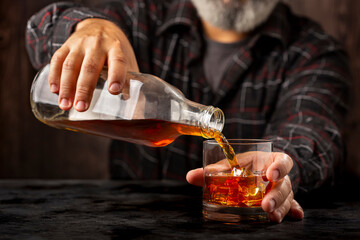 Man filling a glass with whiskey.
