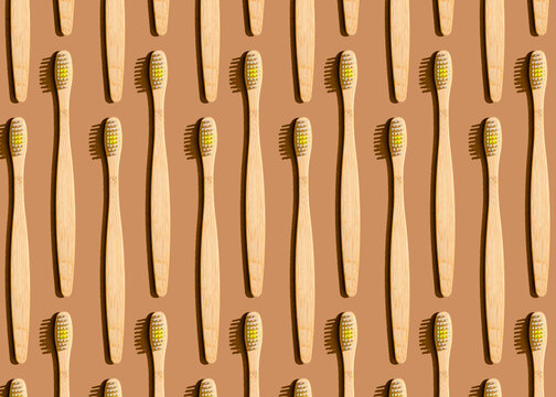 Pattern of wooden toothbrushes flat laid against brown background