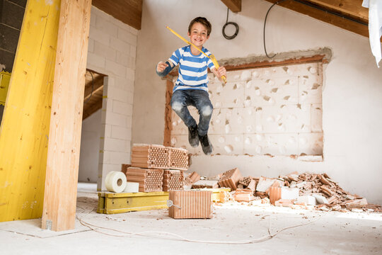 Boy with pocket rule jumping at loft apartment during renovation