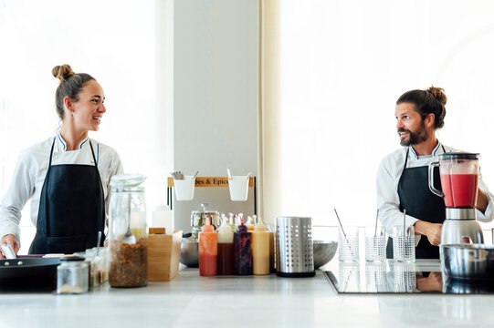 Smiling male and female chefs working in kitchen at restaurant
