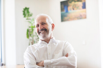 Senior male professional smiling with arms crossed at office