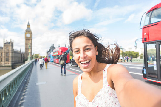 Cheerful woman taking selfie on footpath in London, England, UK