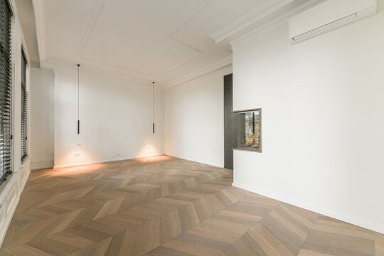 Spacious empty living room with parquet and artificial fireplace