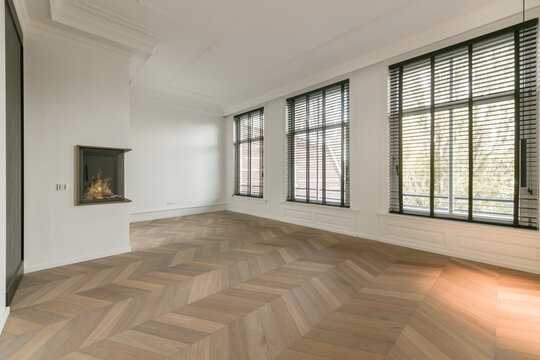 Spacious empty living room with parquet and artificial fireplace
