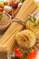 Pasta, vegetables, spices and oil on the table for Italian food