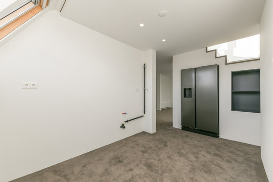 Basement space with white walls and built-in refrigerator and concrete floor
