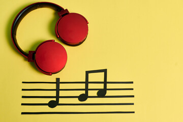 Notes of music and red headphones on a yellow background