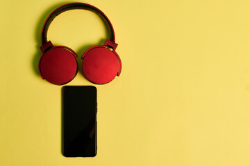 Phone and red headphones on a yellow background
