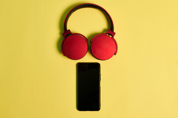 Phone and red headphones on a yellow background