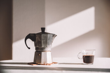 Glass of coffee with pot served on table in daylight