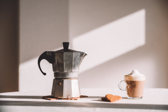 Glass of latte macchiato with moka pot served on table in daylight