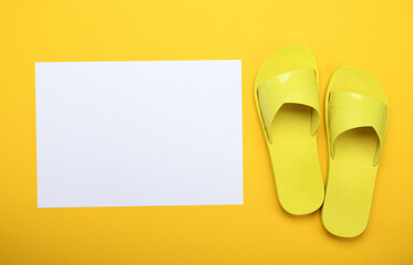 Yellow slippers on a yellow background with a white sheet of paper. 