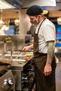 Cook preparing food in deep fryer in kitchen