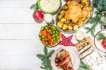 Festive Christmas dinner table with traditional foods and dished – baked ham, chicken, roasted carrots and brussels sprouts, potato, with Christmas decor and gifts 