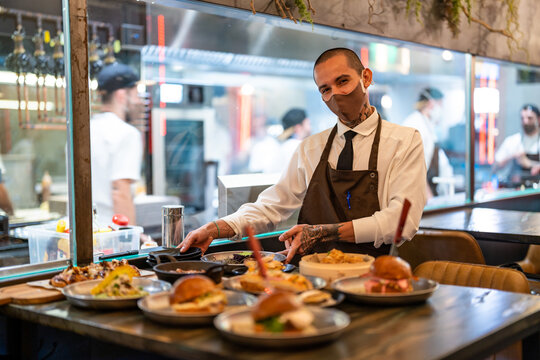 Waiter serving tale with different dishes in restaurant