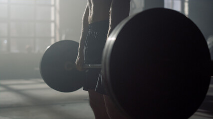 Man preparing sports equipment for workout. Athlete lifting barbell 