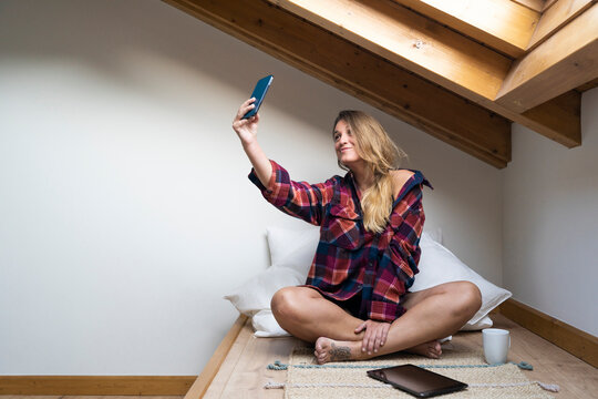Blogger woman taking selfie on smartphone while sitting on floor