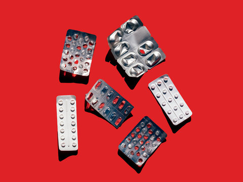 Empty pill blisters on red surface
