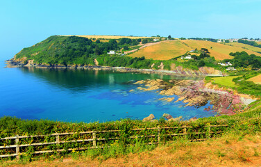 Fototapeta premium Talland Bay Cornwall UK with colourful red and purple rocks and clear sea