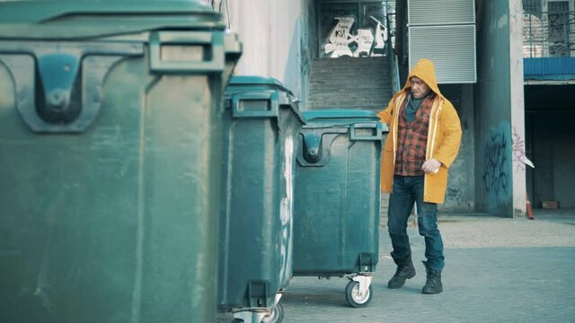 A homeless man is rummaging in the waste bins
