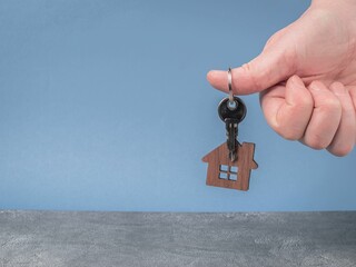 Keys with a model of a wooden house in a man's hand close-up. Home buying concept. Copy space