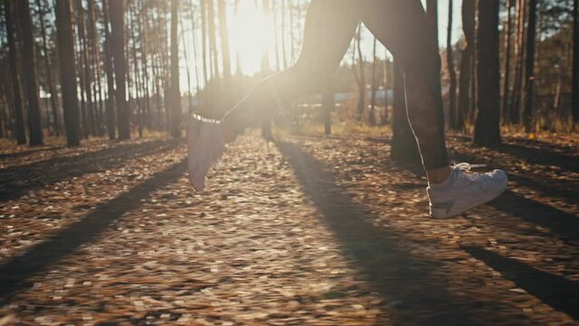 Young woman jogging on trail in autumn forest at sunrise. Slow motion 4k.
