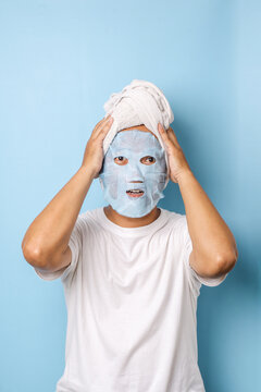 Man with cosmetics mask on the face on blue background. Photo of man with perfect skin. Beauty and Skin care concept
