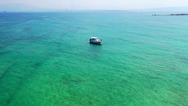 Aerial Beautiful Shot Of Nautical Vessel In Sea, Drone Flying Backwards Over Tourist Swimming In Sea During Vacation - Tripoli, Lebanon