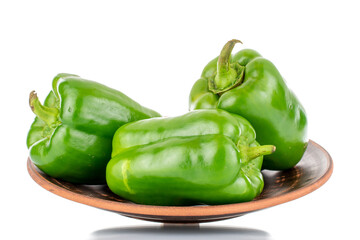 Three sweet green peppers on a clay plate, close-up, isolated on white.