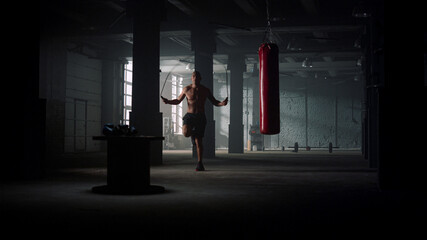 Male boxer jumping on skipping rope. Man with naked torso using jump rope