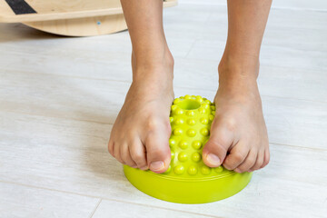 The child performs exercises on the balancer from the valgus of the foot. The child's legs are...