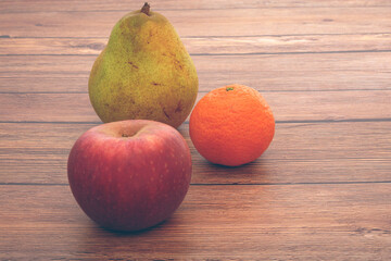 Apple, Pear And Clementine On Wood