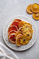 Homemade dried fruit slices of orange, grapefruit, pineapple in a plate. Healthy snack or dessert.