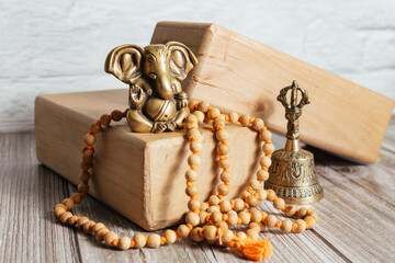 Close-up bronze statue of hindu god of success Ganesha. Japa Meditation accessories, bell and yoga wooden blocks on wooden background.