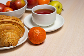 Delicious and healthy breakfast on a white table. A cup of tea with pastries and fruits.