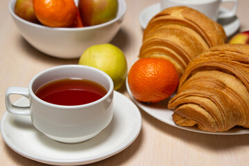 Delicious and healthy breakfast on a white table. A cup of tea with pastries and fruits.