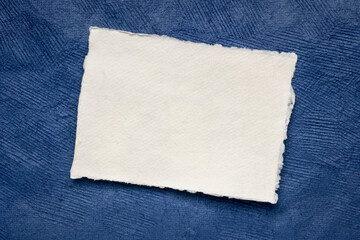 small sheet of blank white Khadi rag paper from South India against blue textured bark paper