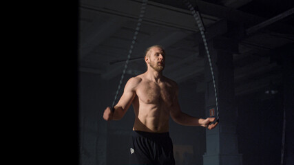 Fototapeta na wymiar Man using jump rope for training in gym. Guy performing jumps on skipping rope