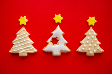 Naklejka na ściany i meble Christmas tree cookies with icing and stars. Festive winter pastry, red background