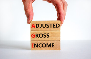 AGI adjusted gross income symbol. Concept words AGI adjusted gross income on wooden blocks. Beautiful white background, businessman hand, copy space. Business and AGI adjusted gross income concept.
