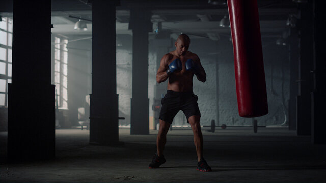 Man doing boxing training in fighting club. Boxer fighting with punching bag - Powered by Adobe
