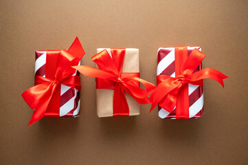 Gift boxes with red bows on brown background, flatlay. Christmas abstract concept.
