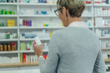 Senior female patient in a pharmacy holding medicament in a hand