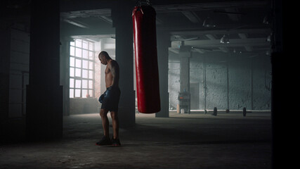 Boxer kicking punch bag during training. Man practicing kicks on sports bag